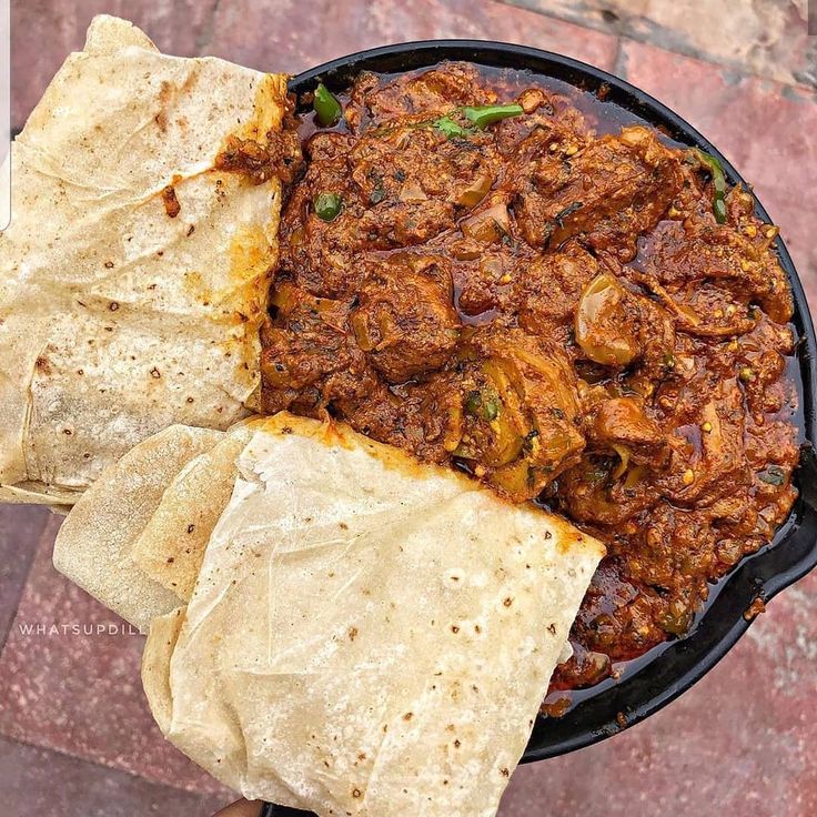 a person holding a tortilla with meat in it