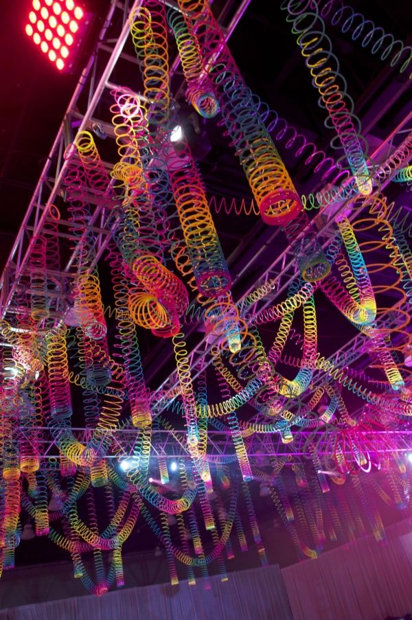 an art installation is lit up at night with colorful lights and spirals hanging from the ceiling