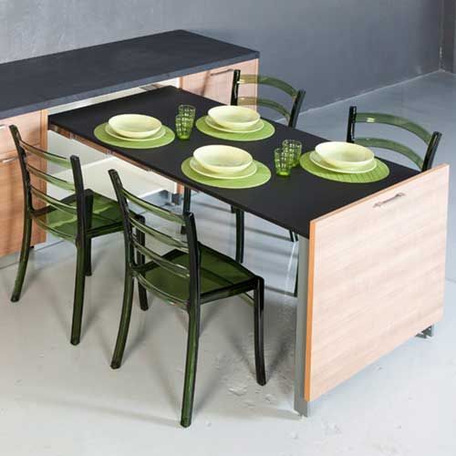 a kitchen table with four chairs and plates on it, in front of a counter