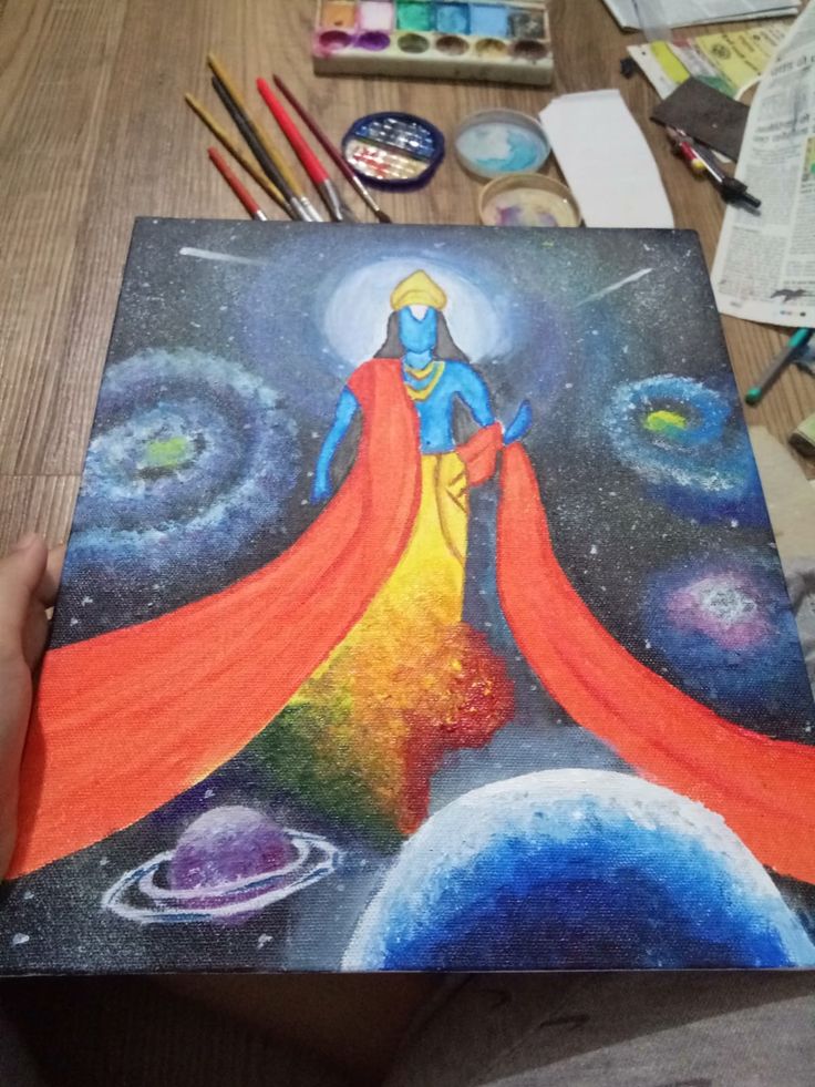 a person holding up a piece of art with space and planets in the back ground