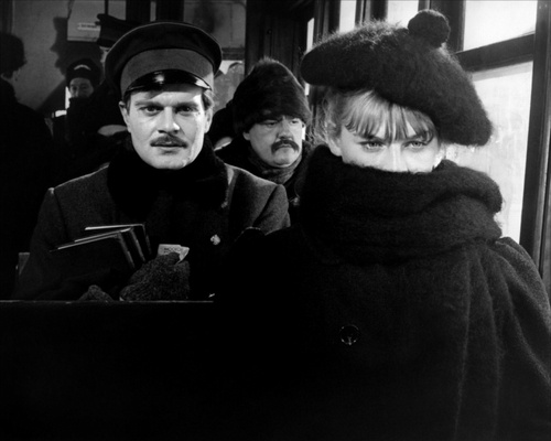 black and white photograph of two people on a subway train, one wearing a hat and scarf