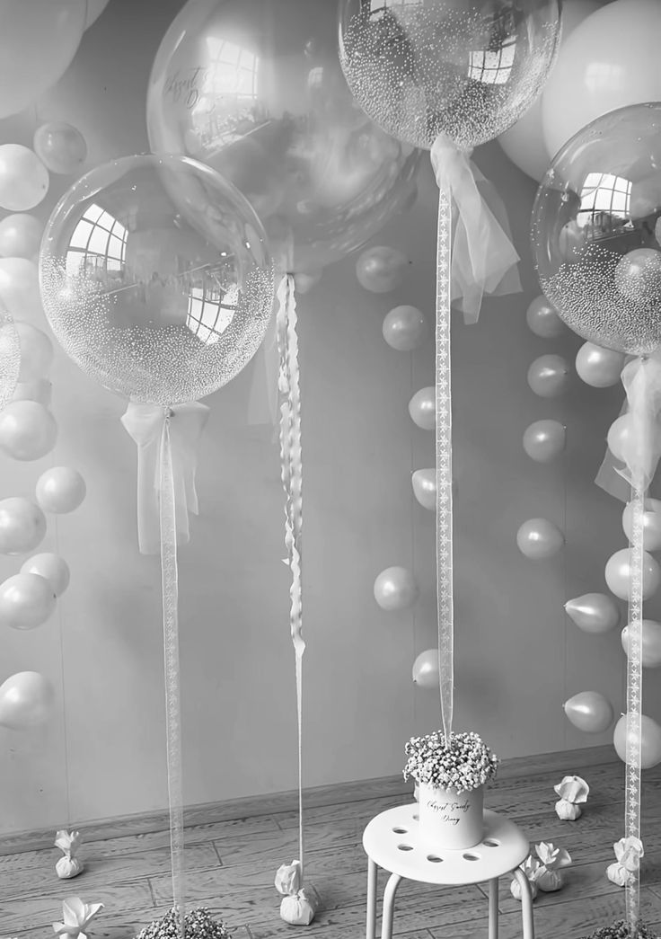 black and white photograph of balloons, chairs and table in front of wall with mirror ballons