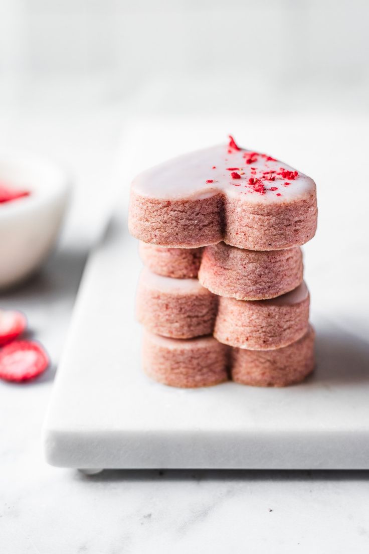 a white plate topped with cookies covered in frosting and red sprinkles