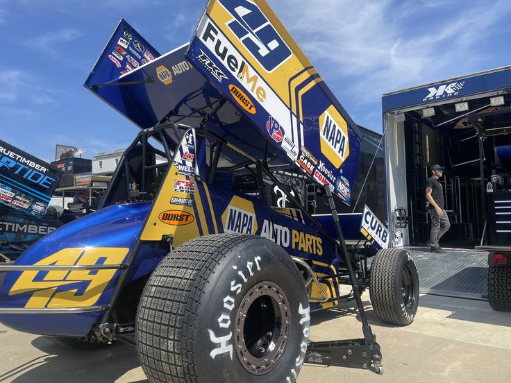 a blue and yellow race car sitting on top of a dirt track