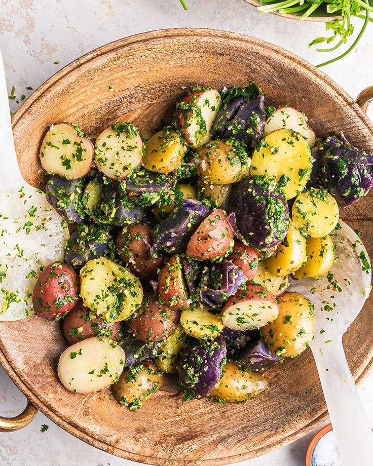 a wooden bowl filled with potatoes and herbs