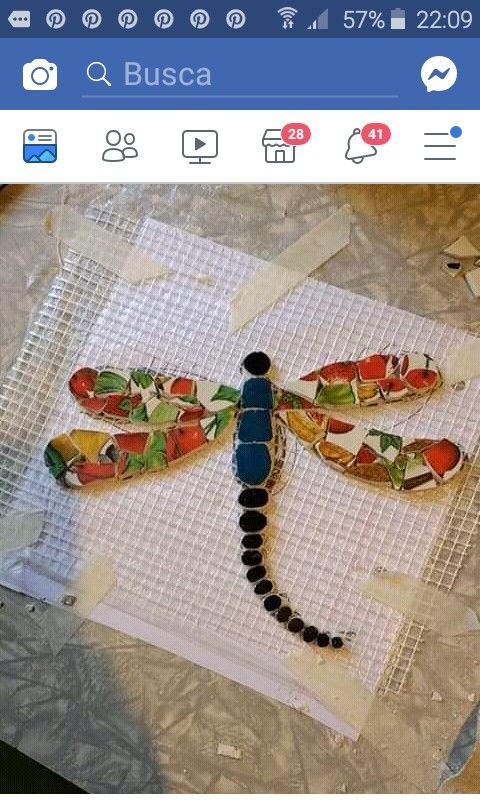 a dragonfly made out of stained glass sitting on top of a piece of paper