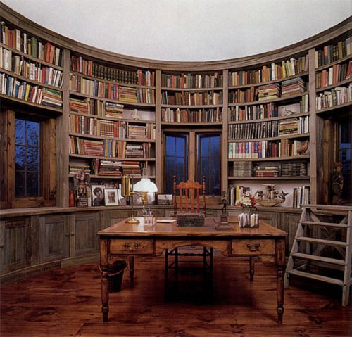 a room with many bookshelves and wooden tables in it, all full of books