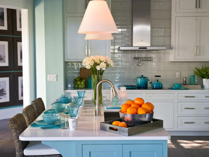 a kitchen with blue cabinets and white counter tops, an island in the middle has oranges on it