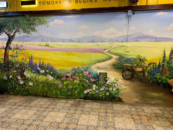 a mural painted on the side of a wall in a train station next to a bench