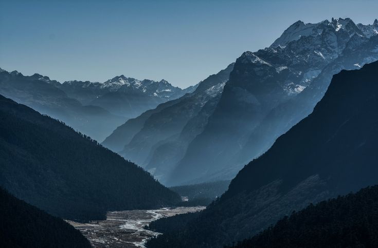 the mountains are covered in snow and light blue hues, as seen from an overlook point