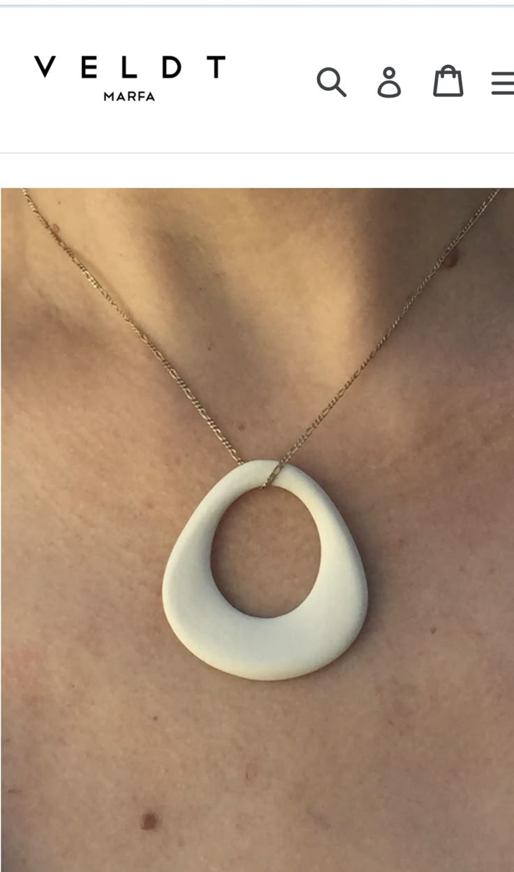 a woman wearing a white necklace with an oval design on it