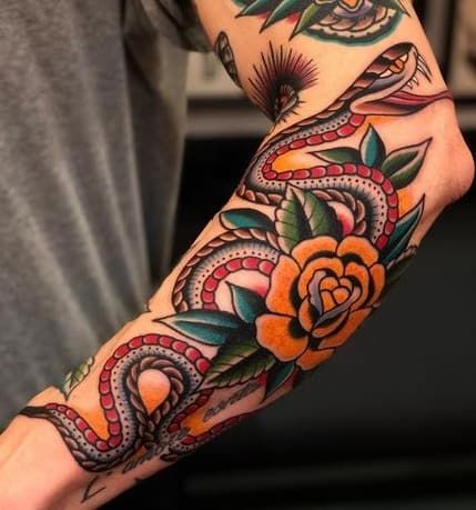 a man with a snake and rose tattoo on his arm is holding an orange flower