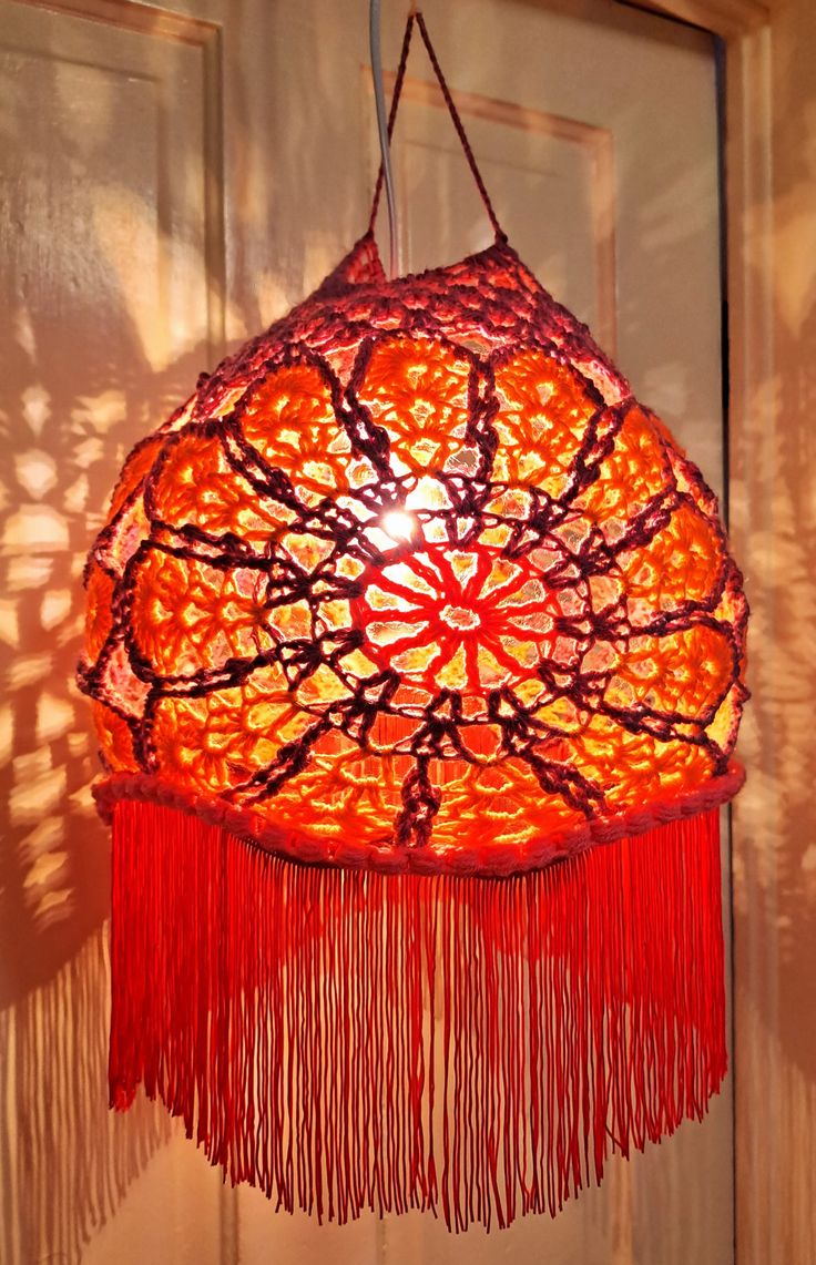 a red lamp hanging from the ceiling in front of a door with shadows on it