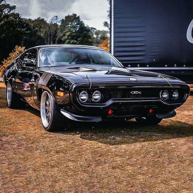 an old muscle car is parked on the grass