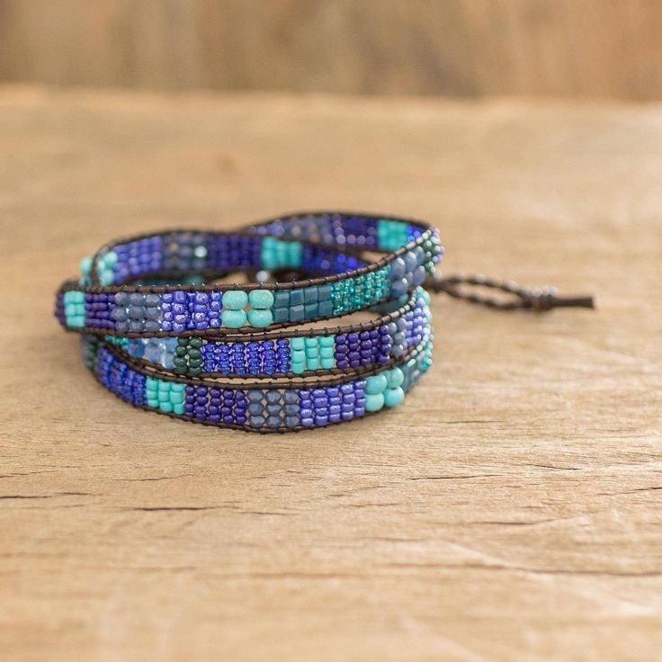 The nimble hands of the Wakami cooperative of Guatemala weave blue and sea green beads into a classic bracelet bound by two cords of leather used to form the button clasp. The beads are made of glass and reconstituted turquoise and woven into a kind of checkerboard pattern with colors and sparkles reminiscent of the ocean. Handmade Artisan Blue Wrap Bracelet, Artisan Handmade Blue Wrap Bracelet, Handmade Blue Wrap Bracelet, Blue Artisan Adjustable Beaded Bracelet, Artisan Blue Adjustable Wrap Bracelet, Adjustable Artisan Blue Beaded Bracelets, Adjustable Blue Artisan Beaded Bracelets, Adjustable Blue Multi-strand Wrap Bracelet, Adjustable Multi-strand Blue Wrap Bracelet