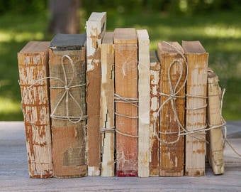 four books tied together with twine and rope on top of each other, sitting on a wooden table