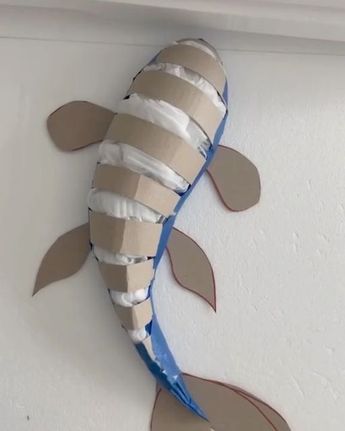 a fish made out of cardboard sitting on top of a wall