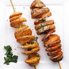 several skewers of food on a white plate with parsley sprigs