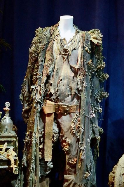 an elaborately decorated suit and hat on display in front of a blue curtained background