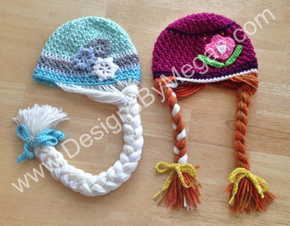 two crocheted hats are laying next to each other on a wooden surface,