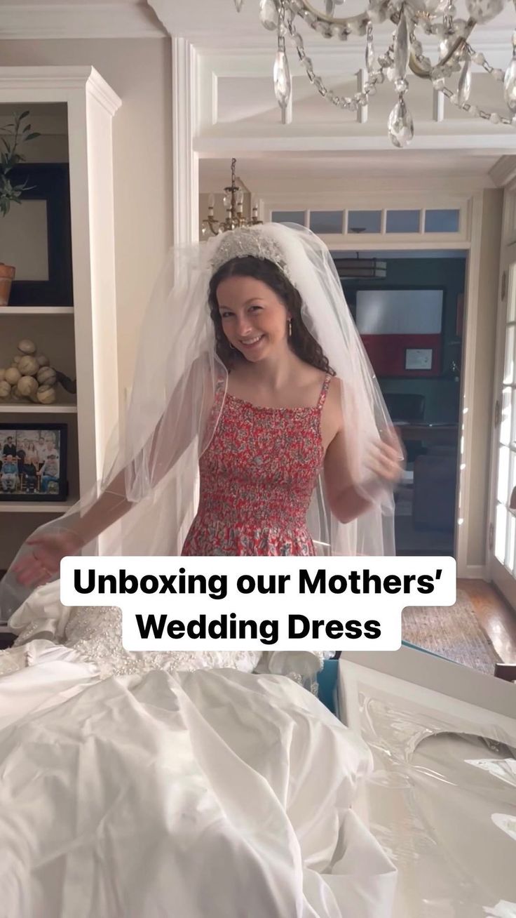 a woman in a wedding dress standing next to a bed with the words unboxing our mothers'wedding dress