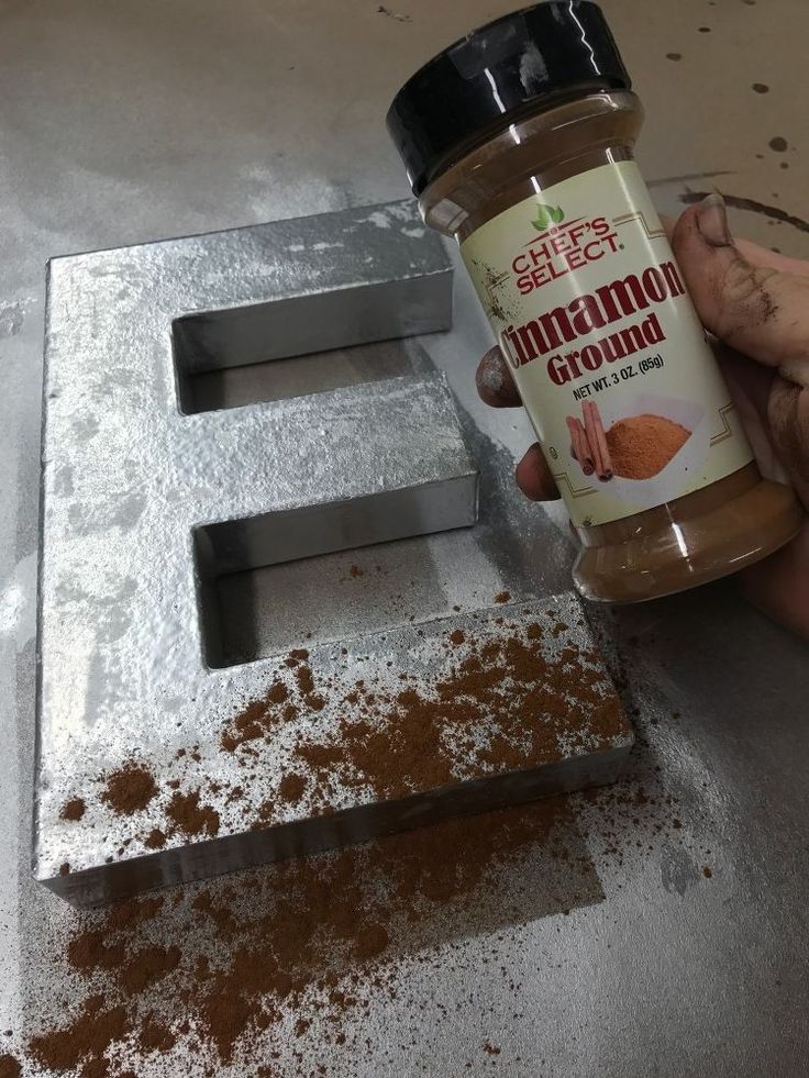 a person holding a jar of peanut butter next to a metal letter sign that reads e