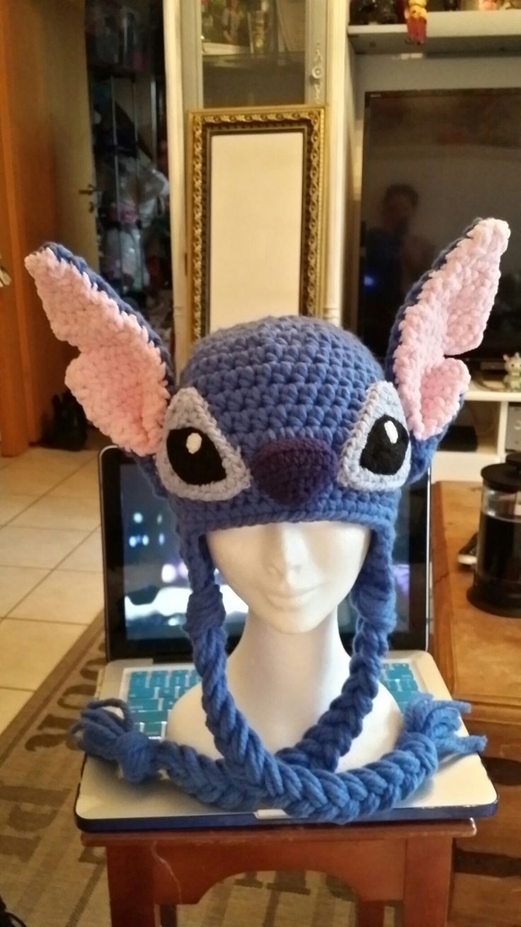 a crocheted hat with ears and eyes on top of a mannequin's head