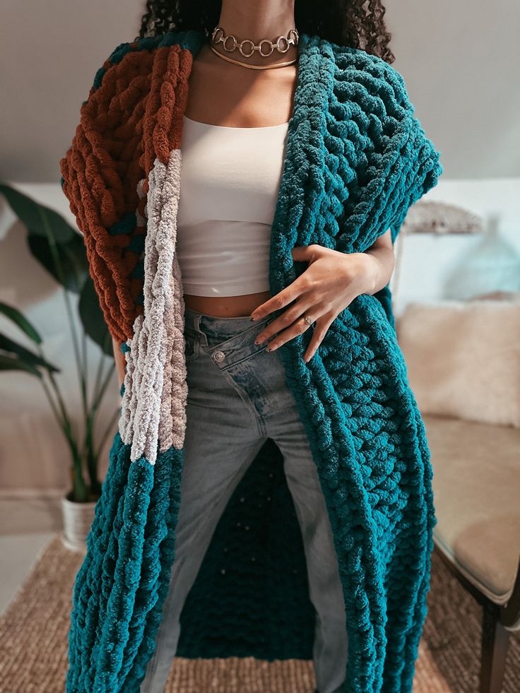 a woman standing in front of a couch wearing a blue knitted cardigan