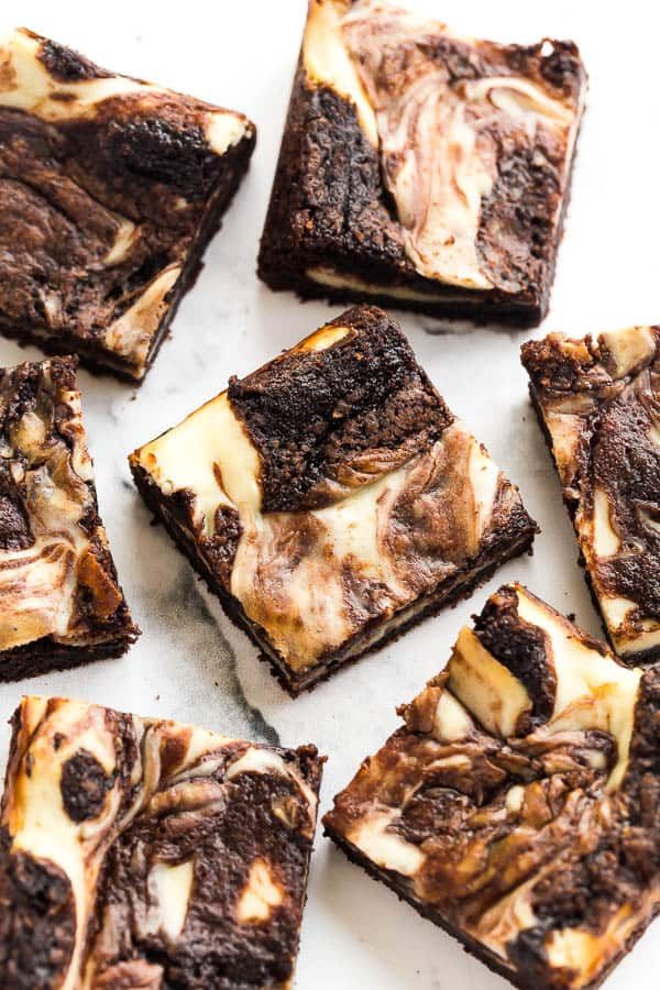 chocolate brownies with marshmallows are arranged on a white counter top, ready to be eaten