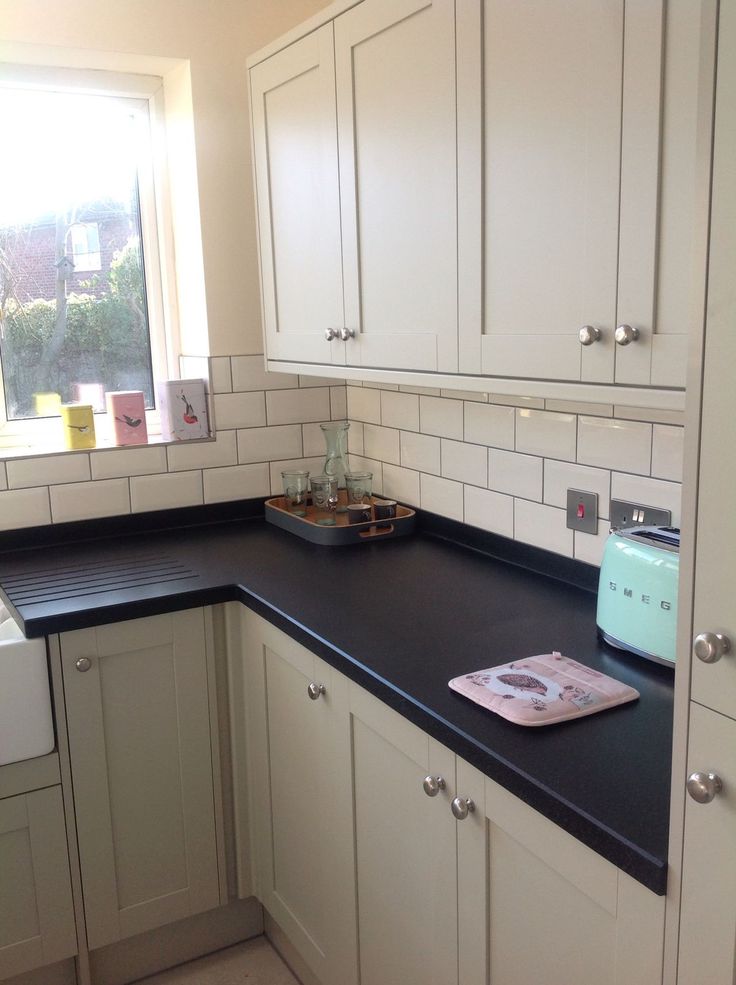 a black counter top in a kitchen next to white cupboards and a dishwasher