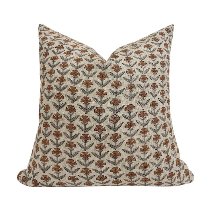 a brown and white pillow with an embroidered flower pattern on the front, sitting on a white background