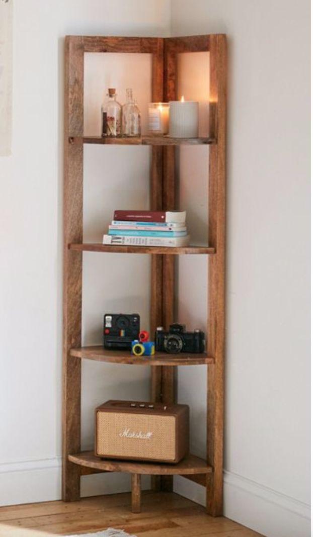 a wooden shelf with books and other items on it in the corner of a room