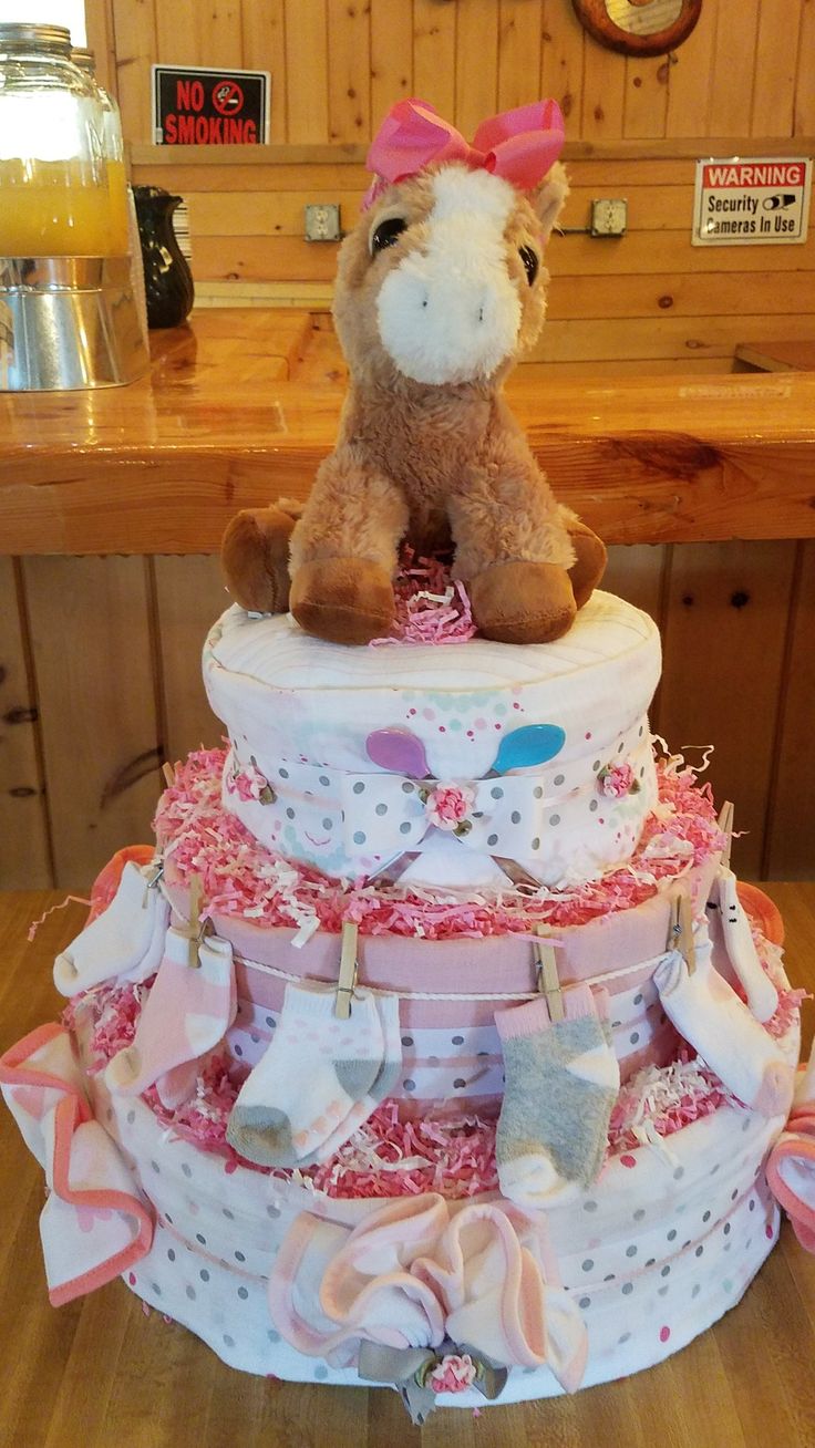 a teddy bear sitting on top of a diaper cake with pink and white ruffles