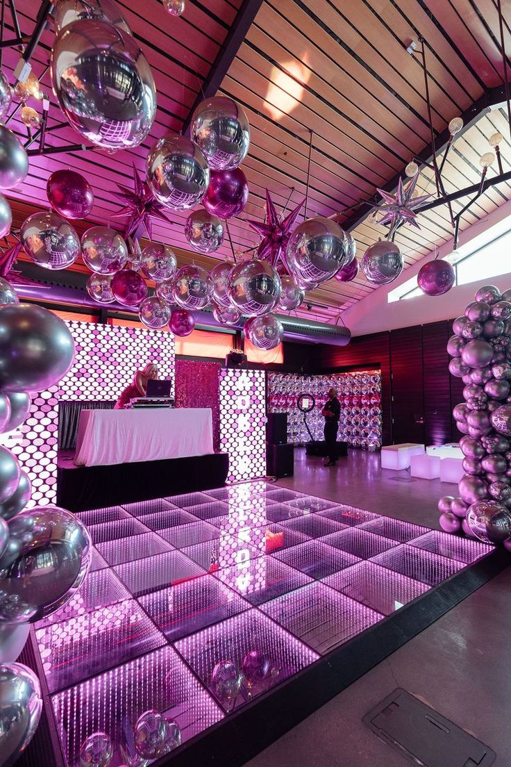 a room filled with lots of balloons and disco balls hanging from the ceiling above it