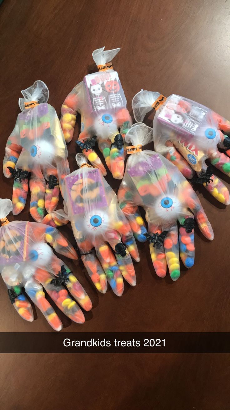 many different colored gloves on a table with candy in them and the text grandkids treats 2021