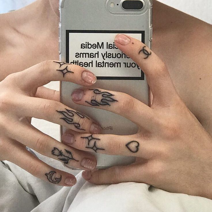 a woman with tattoos on her hands holding a cell phone in front of her face