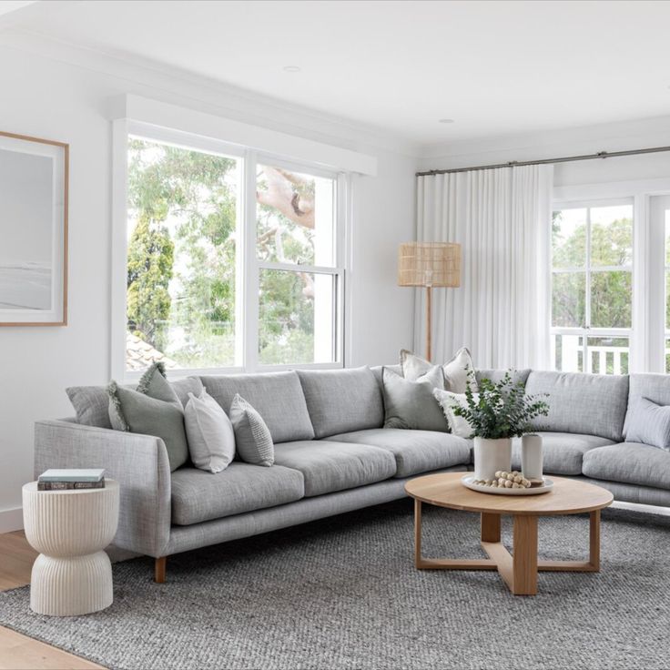 a living room filled with furniture and lots of window sill space next to a wooden coffee table