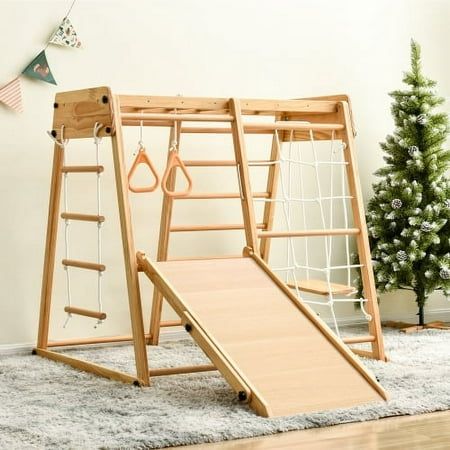 a wooden swing set with two swings and a slide on the floor in front of a christmas tree