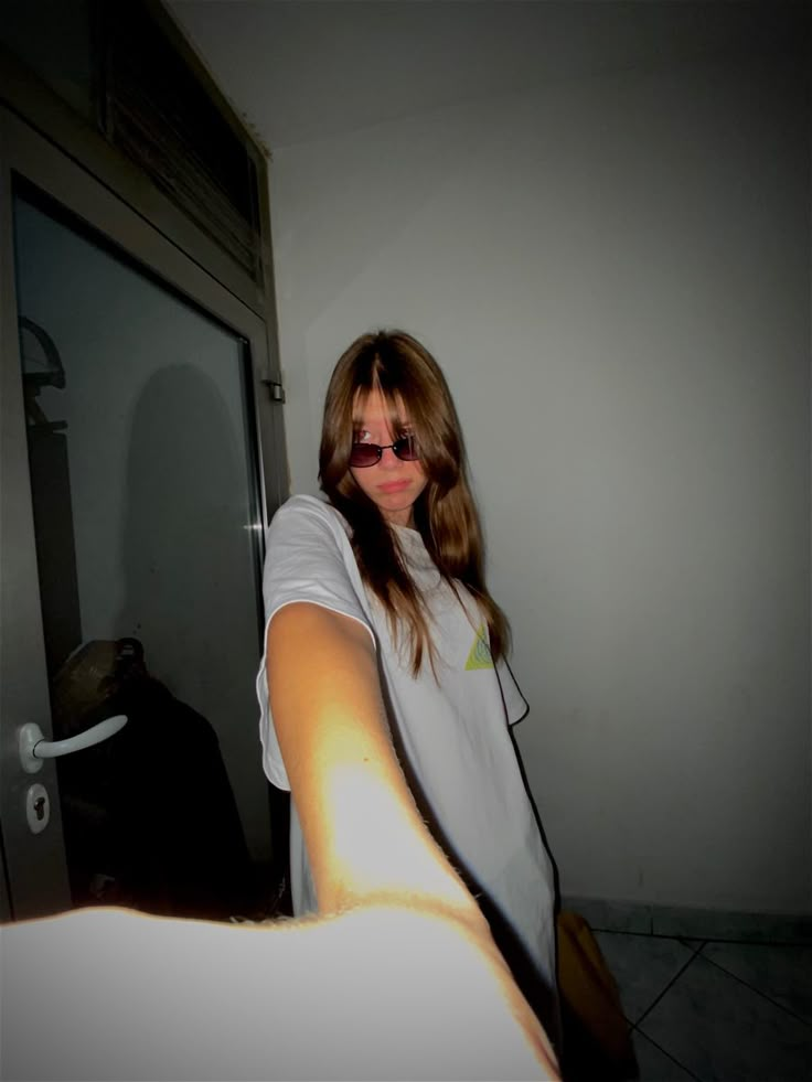 a woman wearing sunglasses is standing in front of an open door and holding her arm out