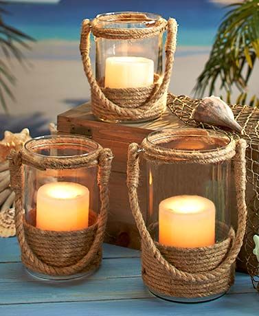 three lit candles sitting on top of a wooden table next to a basket with seashells