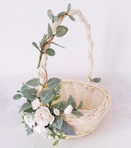 a basket filled with flowers and greenery on top of a table