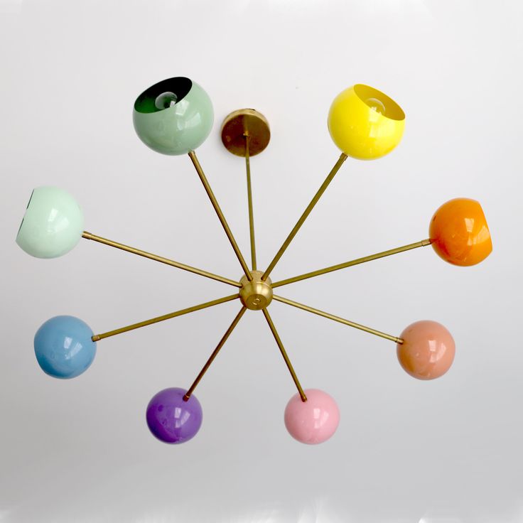 a bunch of different colored balls hanging from a metal rod on a white wall in the shape of a star