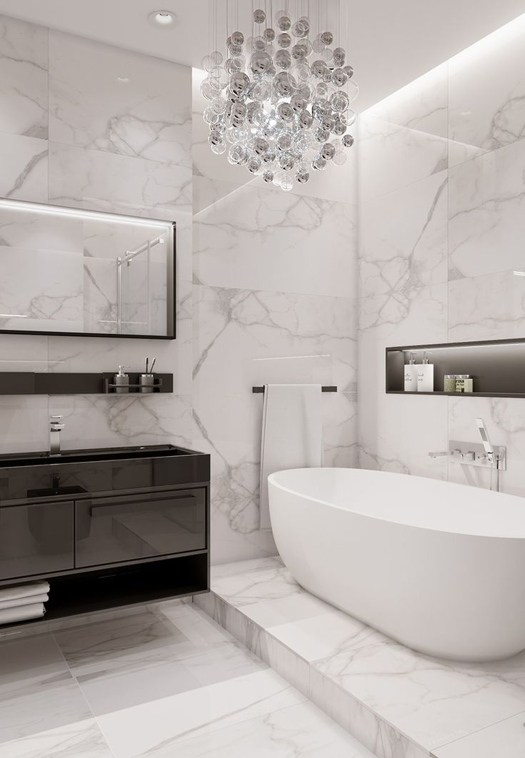 a white bathtub sitting under a chandelier in a bathroom