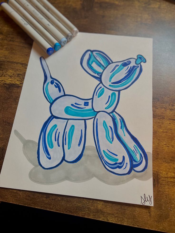 a drawing of a blue dog on white paper with colored pencils next to it