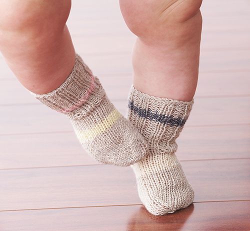 a child's legs with socks on sitting on a wooden floor