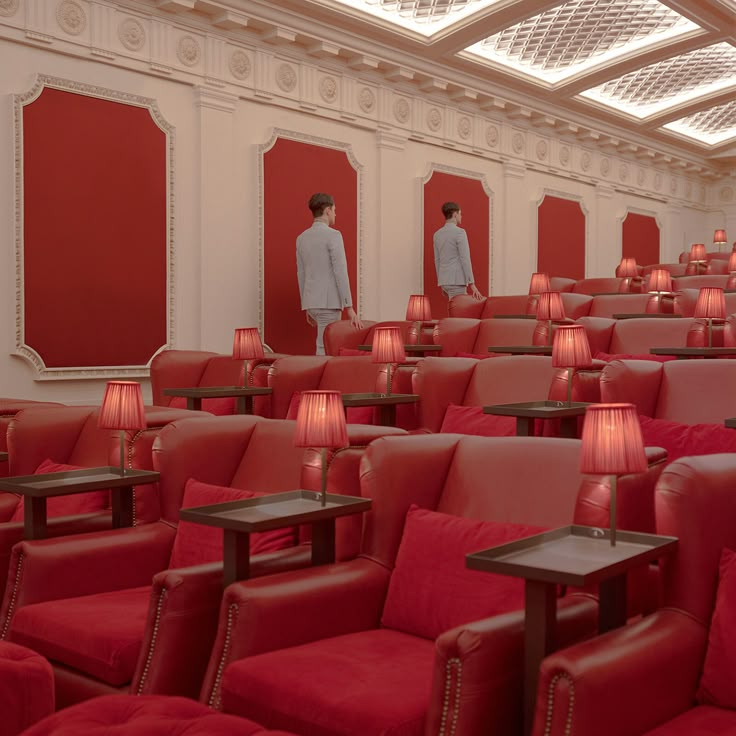 two men in white suits are standing next to each other near red chairs with lamps on them