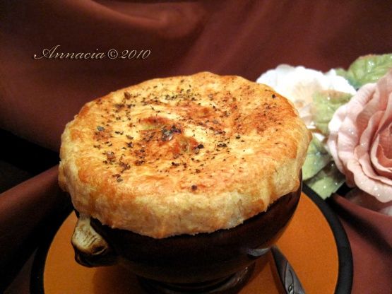 a pot pie sitting on top of an orange plate next to a flower and knife