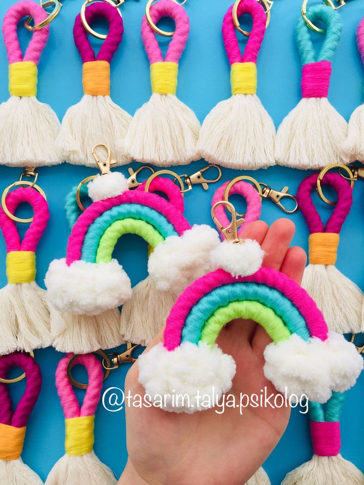 a hand holding a rainbow keychain with tassels