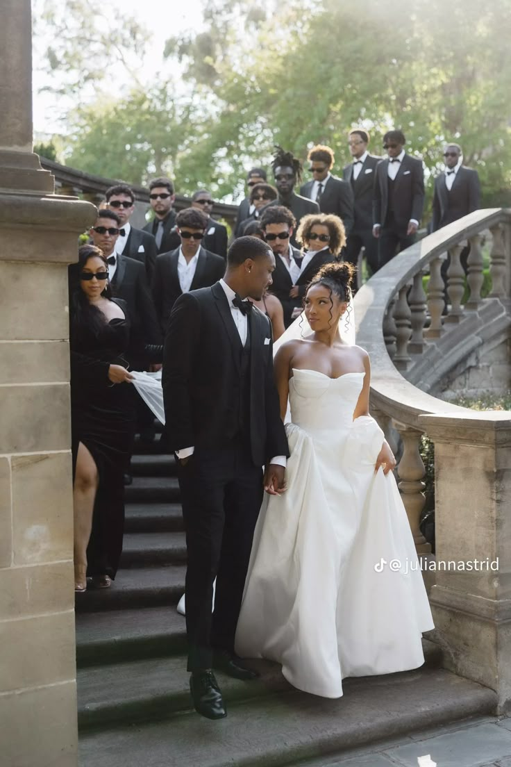 a bride and groom are walking down the stairs at their wedding ceremony in front of a group of people