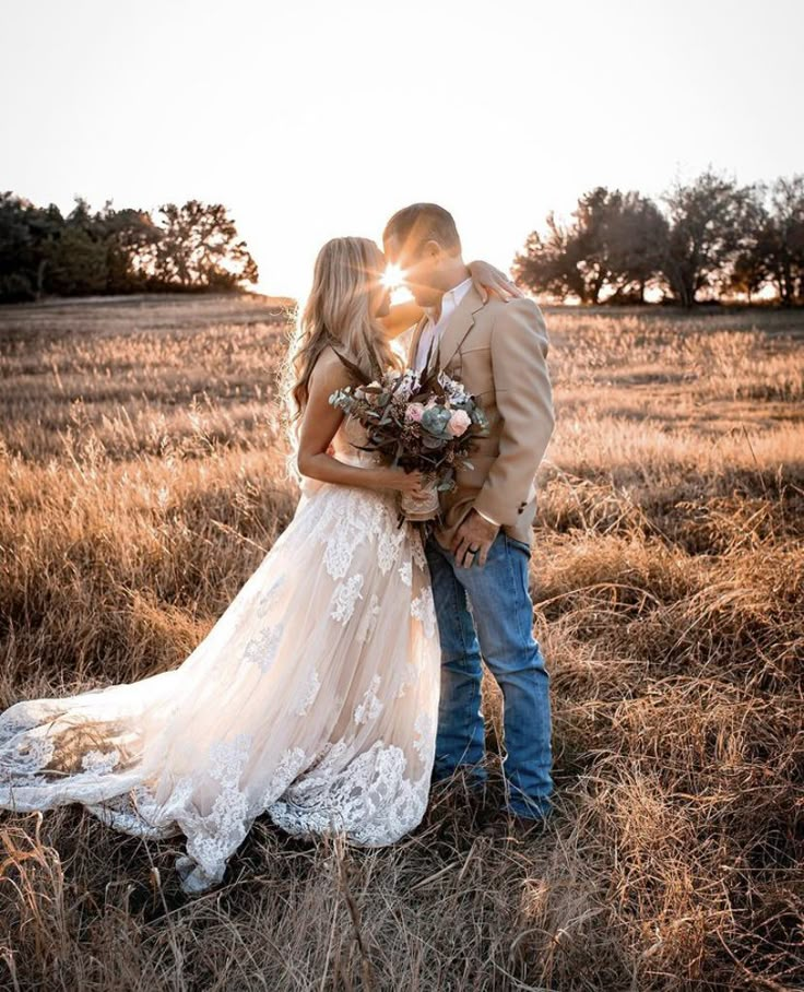 a bride and groom kissing in an open field at sunset with the sun shining behind them